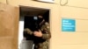 A still image taken from video shows a masked law enforcement officer addressing journalists during a raid in a local office of Kremlin critic Alexei Navalny, in Perm, Russia, Sept. 12, 2019.