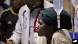 A woman cradles the head of a young patient injured in a grenade attack at a downtown bus station, at Kenyatta Hospital in Nairobi, Kenya, March 10, 2012. 