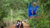 រូបឯកសារ៖ ក្មេងៗ​សិស្សសាលា​ជិះកង់​កាត់​ស្លាកសញ្ញា​នៃ​មេដឹកនាំគណបក្ស​ប្រជាជនកម្ពុជា ដែល​មាន​រូប​លោកនាយករដ្ឋមន្រ្តី ហ៊ុន សែន ជា​ប្រធានគណបក្ស និង​ លោក ហេង សំរិន ប្រធាន​រដ្ឋសភា នៅ​តាម​ផ្លូវ​ក្នុង​ភូមិ​បន្ទាយមាស ឃុំ​តាជេស ស្រុក​កំពង់ត្រឡាច ខេត្តកំពង់ឆ្នាំង។ រូបថត​ថ្ងៃ​ពុធ ទី​៨ ខែ​វិច្ឆិកា ឆ្នាំ​២០១៧។ (ស៊ុន ណារិន/VOA)