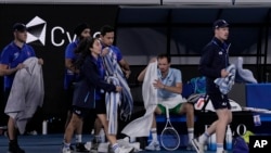 Trabajadores se alistan para secar las canchas cerca del puesto de Daniil Medvedev de Rusia en su partido contra Learner Tien de EEUU en el Abierto de tenis de Australia, en Melbourne, en las primeras horas del 17 de enero de 2025. (Foto AP/Ng Han Guan).