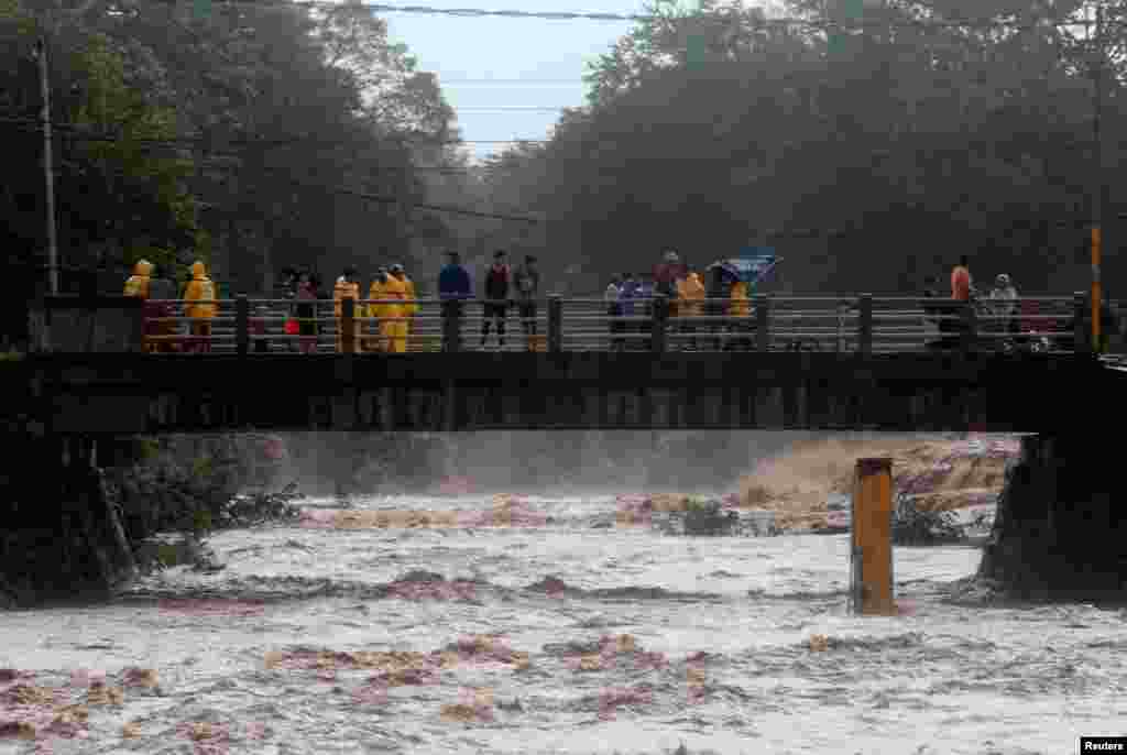 Un grupo de personas se para en el puente que cruza el r&#237;o Masachapa bajo la lluvia causada por la tormenta Eta en Masachapa, Nicaragua, 4 de noviembre de 2020.
