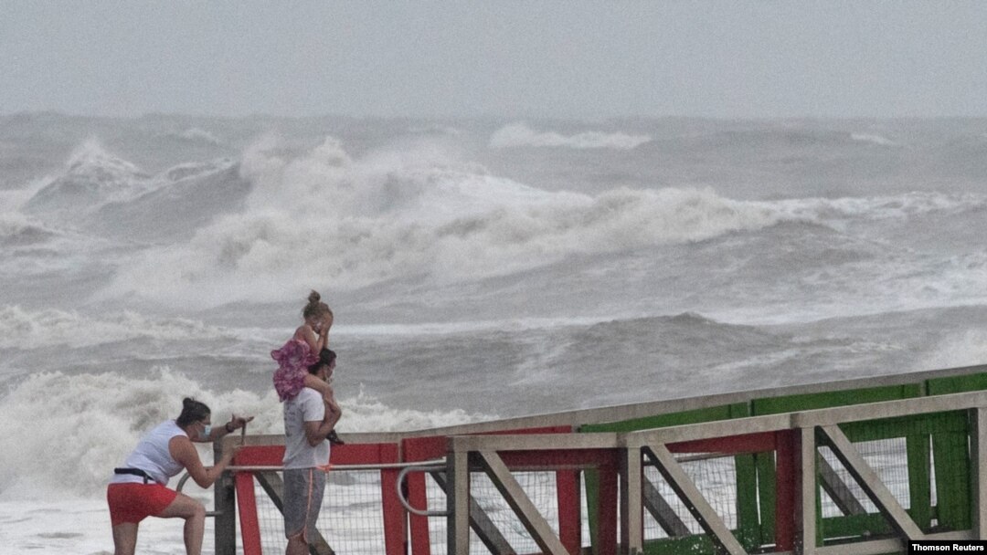 A family watches high swells from Hurricane Hanna from a jetty in Galveston, Texas