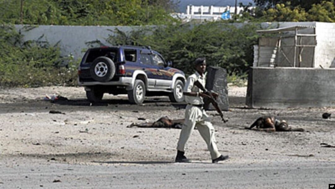 Somali police officers walk past bodies of two civilians who were killed during a suicide-bomb attack targeting Mogadishu international airport, 09 Sep 2010