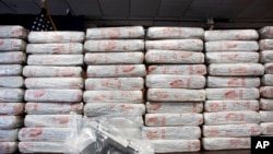 A firearm and 154 pounds of heroin worth at least $50 million are displayed at a Drug Enforcement Administration news conference, May 19, 2015 in New York.