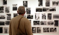 FILE - A man looks at prints from the Looking In: Robert Frank's "The Americans" exhibit at the Museum of Modern Art in San Francisco, May 18, 2009.