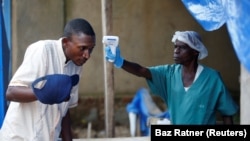 Un agent de santé mesure la température d'un homme entrant dans le centre de traitement d'Ebola d'ALIMA à Beni, en République démocratique du Congo, le 1er avril 2019.