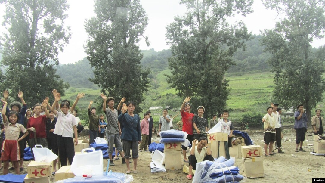 A handout photo dated July 31, 2012 shows North Korean residents waving as they receive relief goods from DPRK Red Cross Society (RCS) after rain-triggered floods hit Songchon county, South Pyongan Province.
