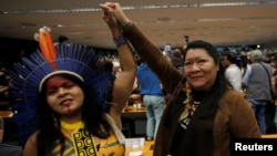 Congresswoman Joenia Wapichana, right, of the Wapixana tribe and Indigenous Leader Sonia Guajajara of the Guajajara tribe raise their hands during a meeting with congressmen in Brasilia, April 25, 2019.