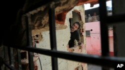 Abelino Vieira inspects the hole where looters entered his grocery and liquor store during a protest in Caracas, Venezuela, April 12, 2017.