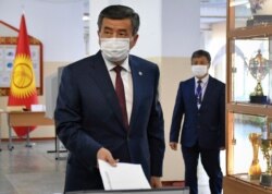 Kyrgyzstan's President Sooronbai Jeenbekov wearing a face mask casts his ballot paper during parliamentary elections in Bishkek, Kyrgyzstan, Sunday, Oct. 4, 2020.