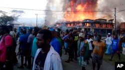 Warga Papua berkumpul di dekat toko yang terbakar dalam aksi protes di Wamena, provinsi Papua, 23 September 2019. 