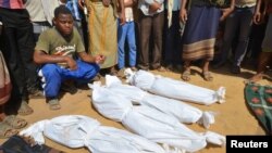 FILE - A man sits as others stand near the wrapped up bodies of children from the same family, one day after they were killed in a Saudi-led airstrike on their house in Bajil district of the Red Sea province of Houdieda, Yemen, Oct. 8, 2016. 