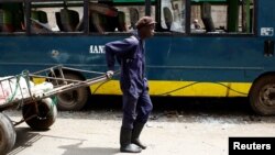 A man pulling a cart passes next to a bus vandalized during the latest protests in Mathare, Nairobi, Kenya, August 14, 2017. 