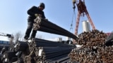 Workers use a crane to lift steel rebar at a steel market in Fuyang, in China’s eastern Anhui province on February 10, 2025. (Photo by AFP) / CHINA OUT