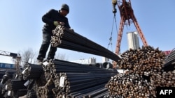 Workers use a crane to lift steel rebar at a steel market in Fuyang, in China’s eastern Anhui province on Feb. 10, 2025.