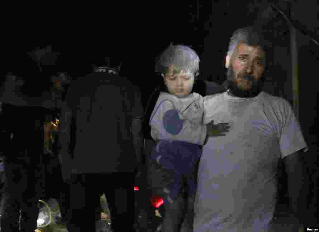 A man holds a wounded child in a building hit by what activists said was a barrel bomb dropped by forces loyal to President Bashar al-Assad, Bustan al-Qasr, Aleppo, May 28, 2014.