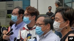 Beberapa terdakwa termasuk aktivis pro-demokrasi, dari kiri, Richard Tsoi, Figo Chan dan Albert Ho saat memberikan keterangan kepada media di luar pengadilan di Hong Kong, Senin, 17 Mei 2021. 