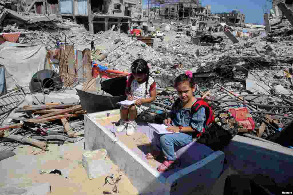 Palestinian students attend a class in a tent set up on the ruins of the house of teacher Israa Abu Mustafa in Khan Younis in the southern Gaza Strip as war disrupts a new school year.