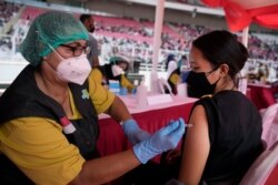 A woman receives a shot of the Sinovac COVID-19 vaccine during a mass vaccination at Gelora Bung Karno Main Stadium in Jakarta, Indonesia, June 26, 2021.