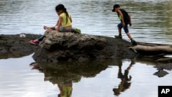 Children play on land partially exposed caused by a drought at the Carraizo reservoir in Trujillo Alto, Puerto Rico, Aug. 5, 2015.