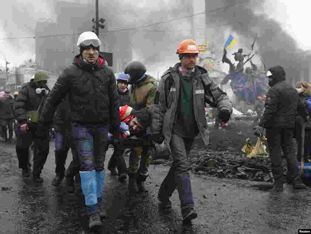 Manifestantes transportam um homem ferido numa maca depois de confrontos com a polícia de choque na Praça da Independência, Kiev,&nbsp; Fev. 20, 2014.