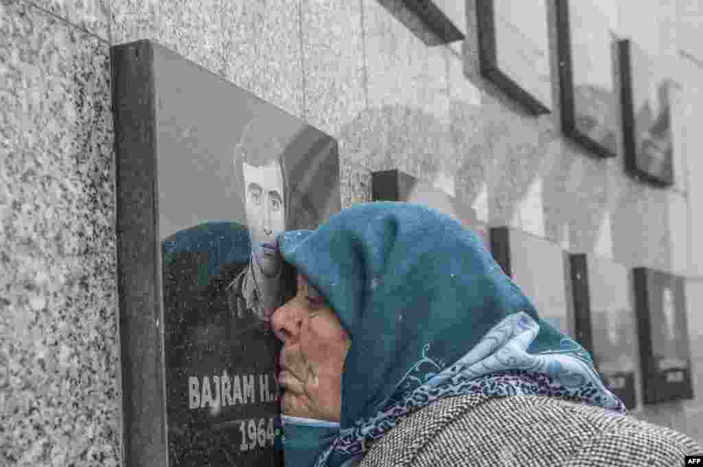 A Kosovo Albanian woman Vezire Gjeladini, 76, kisses the picture of her son etched into a commemorative plaque and placed on a wall dedicated to the victims of the Racak massacre, Kosovo. In 1999, forty-five Albanian civilians were killed by Serb forces, in the village of Racak.