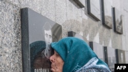 Vezire Gjeladini, 76 vjeçe nga Kosova, puth fotografinë e gdhendur në pllakën përkujtimore që u kushtohet viktimave të masakrës së Reçakut, më 15 janar, 2018/AFP