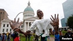 Marchers carry a papier-mache representation of slain Michael Brown with his hands up, during rallies in greater St. Louis, Missouri, Oct. 11, 2014.