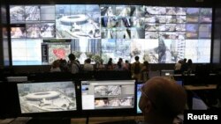 FILE- A policeman observes a screen displaying the Maracana stadium during a media tour at the security center for the 2014 soccer World Cup in Rio de Janeiro, Jan. 22, 2014.