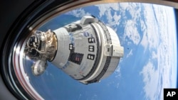 En esta imagen, de la NASA, se muestra la cápsula Starliner de Boeing, acoplada al puerto delantero del módulo Harmony, el 3 de julio de 2024, vista desde una ventana de la nave Dragon Endeavour de SpaceX, acoplada al puerto adyacente.