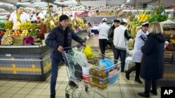 FILE - A man pushes a cart with food items at a grocery store in Moscow, Russia, April 2, 2015.