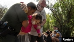 Un agente de la Patrulla Fronteriza de EE. UU. ayuda a una anciana migrante venezolana que busca asilo después de que la mujer cruzó el río Grande hacia los Estados Unidos desde México en Del Rio, Texas, el 26 de mayo de 2021.