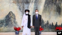 Salah satu pendiri Taliban Mullah Abdul Ghani Baradar (kiri) dan Menteri Luar Negeri China Wang Yi berpose untuk foto dalam pertemuan antara kedua belah pihak di Tianjin, China, pada 28 Juli 2021. (Foto: Xinhua via AP/Li Ran)