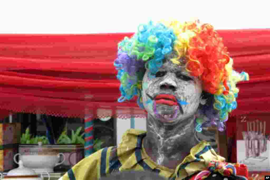 A Nigerian man dressed as a clown tries to attract customers to a market stall, in Lagos, Nigeria, Wednesday, Nov. 16, 2011. (AP Photo/Jon Gambrell)
