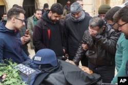 Colleagues and friends mourn over the body of Syrian photographer Anas Alkharboutli, 32, in Idlib, Syria, on Dec. 4, 2024. Alkharboutli, who worked for the German news agency dpa, was killed in an airstrike near the city of Hama, the agency said.