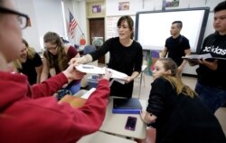 FILE - High school teacher Natalie O'Brien, center, hands out papers during a civics class called "We the People," at North Smithfield High School in North Smithfield, Rhode Island.