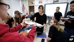 FILE - High school teacher Natalie O'Brien, center, hands out papers on March 8, 2017, during a civics class called "We the People," at North Smithfield High School in North Smithfield, Rhode Island.