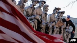 Seniman Sergio Furnari berpose di sebelah patung buatannya “Makan Siang di Atas Gedung Pencakar Langit – Penghormatan Kepada Pahlawan Amerika,” di luar Serikat Pekerja Industri Besi di Washington DC, 20 November 2015.