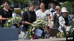 Clifton Truman Daniel (C) offers a wreath of flowers at the memorial cenotaph for the people killed by the atomic bomb at the Peace Memorial Park in Hiroshima, Japan, August 4, 2012.