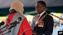 Emmerson Mnangagwa, right, is sworn in as President at the presidential inauguration ceremony in the capital Harare, Zimbabwe Friday, Nov. 24, 2017. Mnangagwa is being sworn in as Zimbabwe's president after Robert Mugabe resigned on Tuesday, ending his 37-year rule. (AP Photo/Ben Curtis)