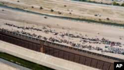 ARCHIVO - Migrantes forman filas fuera de la cerca fronteriza esperando ser transportados a una instalación de la Patrulla Fronteriza de EE. UU. en El Paso, Texas, el 10 de mayo de 2023.