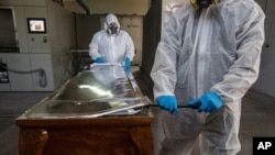 Workers open the coffin of a COVID-19 victim to place his remains into an incinerator, at La Recoleta crematorium in Santiago, Chile, April 16, 2021.