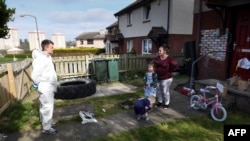 Russel Bowers, seorang relawan (kanan), mengantar makanan untuk Becky Foster (32), dan kedua anaknya di Edinburgh, Skotlandia, di tengah pandemi virus corona, 22 April 2020. (Foto: AFP)