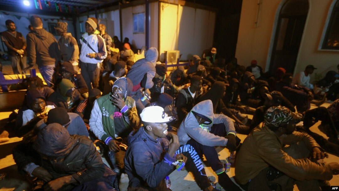 FILE - Migrants sit on the floor at a detention center inTajoura, in the eastern suburbs of the Libyan capital Tripoli, Nov. 29, 2019. 