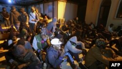 FILE - Migrants sit on the floor at a detention center inTajoura, in the eastern suburbs of the Libyan capital Tripoli, Nov. 29, 2019. 