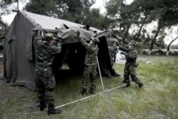 Greek army officers set up tents outside a hotel used as a shelter for refugees and migrants, after authorities found several cases of the coronavirus, in Kranidi, April 21, 2020.