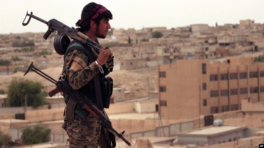 This photo provided by the Syria Democratic Forces (SDF) shows a fighter from the SDF carrying weapons as he looks toward the northern town of Tabqa, Syria, April 30, 2017.