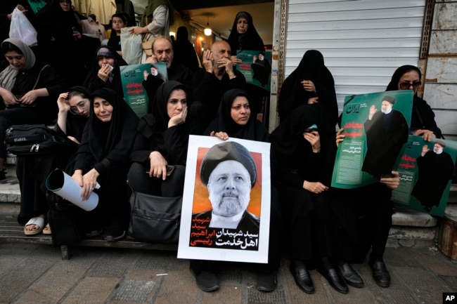 People hold up posters of Iranian President Ebrahim Raisi during a mourning ceremony for him at Vali-e-Asr square in downtown Tehran, Iran, Monday, May 20, 2024. (AP Photo/Vahid Salemi)