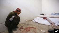 A man mourns next to his dead relative at a morgue, after his body was recovered from the site of a double suicide bombing in Quetta, Pakistan, September 7, 2011.
