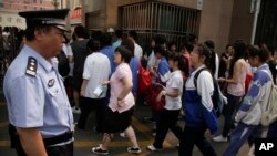 FILE - Chinese students walk past a police officer on their way to the annual college entrance examinations held in Beijing, China.